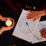 Top view of female fortune teller reading astrology chart for young woman visiting at spiritual seance